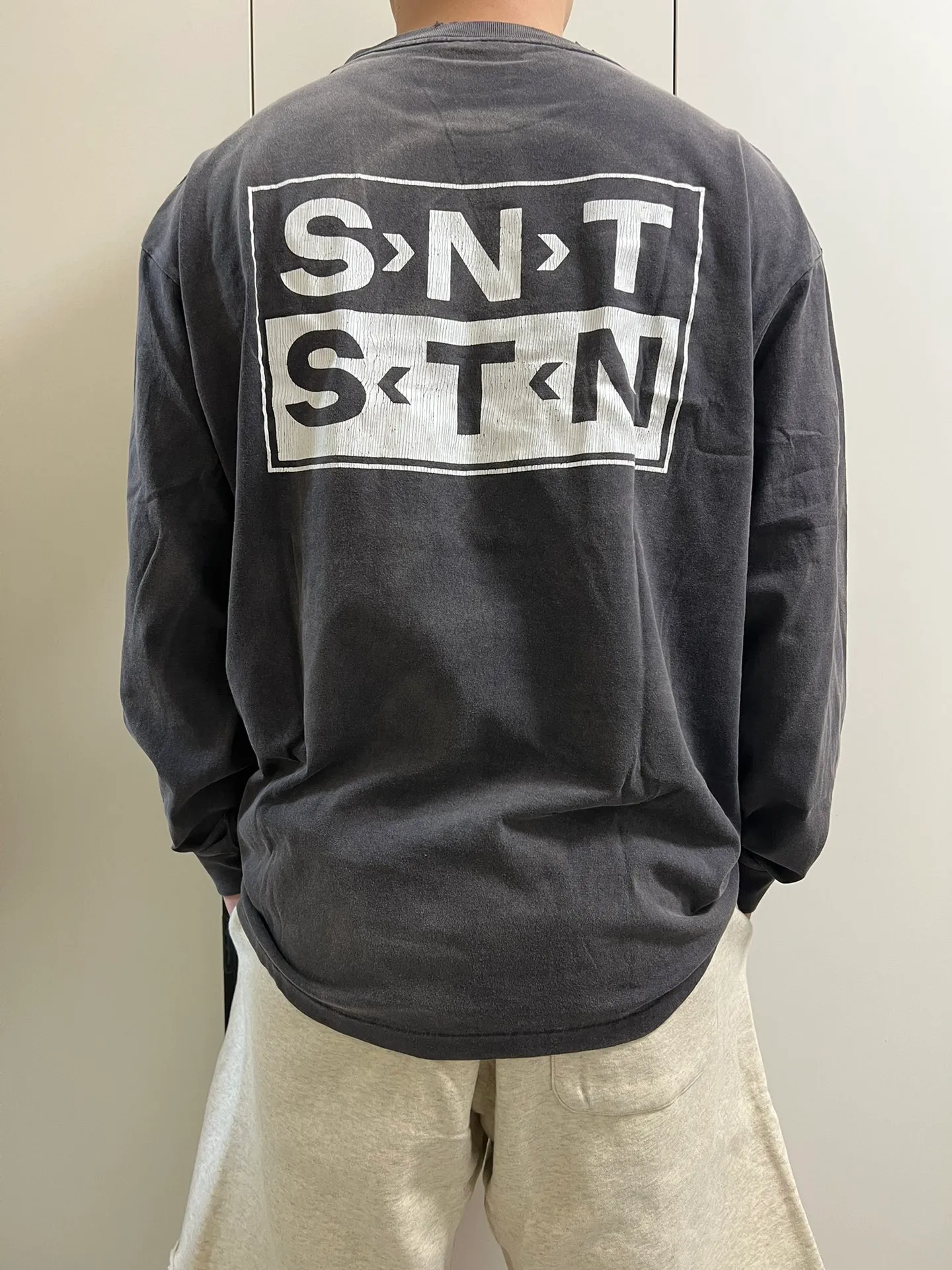 SAINT Mxxxxxx S>N>T LS TEE/BLACK Autumn and winter new style S>N>T slogan crack printed long TEE, washed black S-XL Asut ready-made garments dyed, the whole piece sprayed with horse-hair spray, and then sprayed again to fade the color. The collar and cuffs are frayed. Many hangings are worn NEW VINTAGE. Heavy craftsmanship.